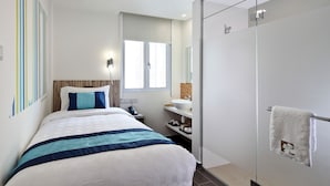 Une chambre d’hôtel moderne équipée d’un lit, d’une table de chevet et d’une douche à parois de verre.