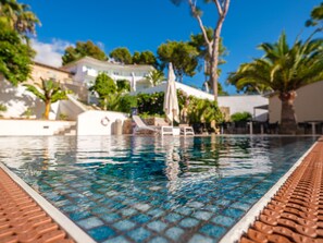 A swimming pool with a tiled edge, lounge chairs, and palm trees. - Tacande Portals Hotel  (Calvia)