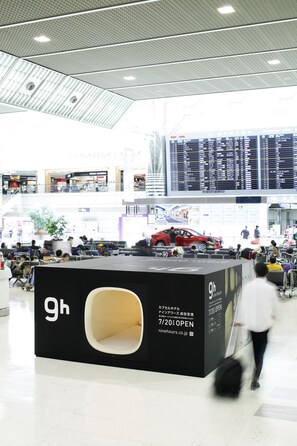 A modern airport terminal with a 9h kiosk, a digital flight information display, and a red car model. - 9h nine hours Narita Airport (Narita)