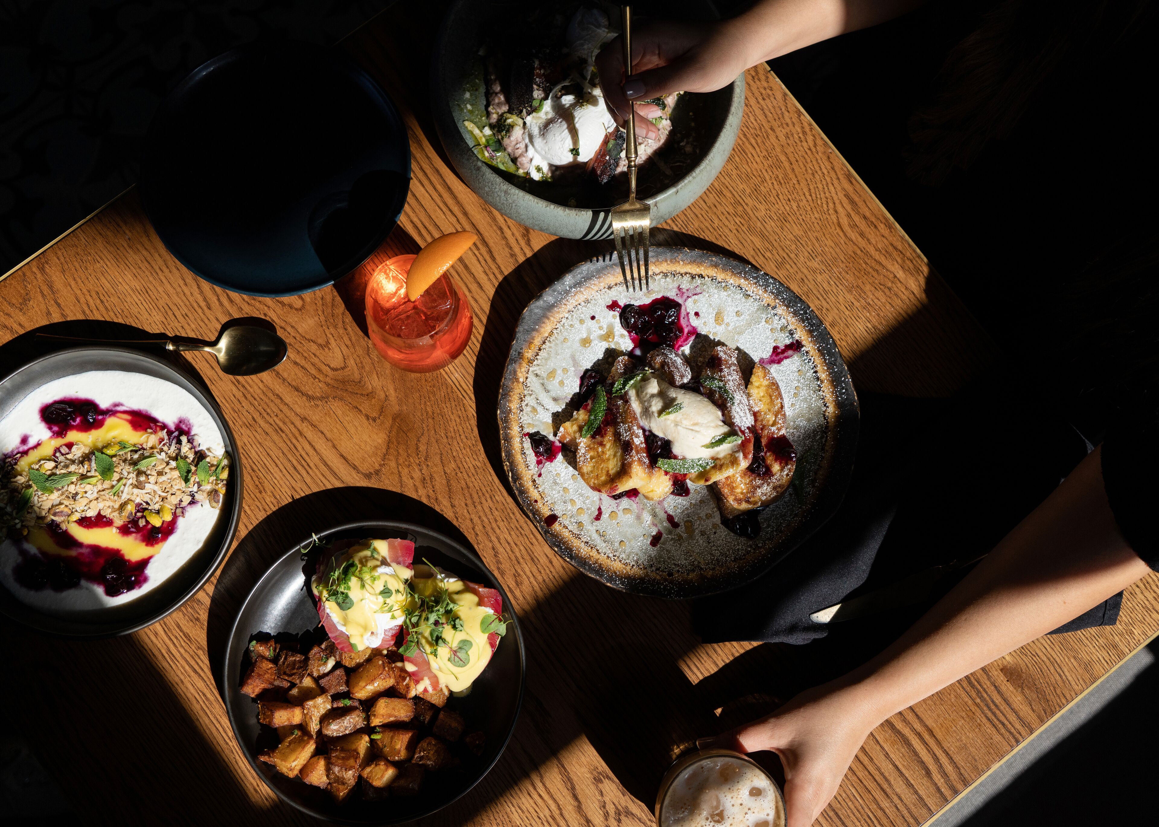 Une table en bois sur laquelle on trouve différents plats, notamment une assiette de crêpes et un verre de bière.