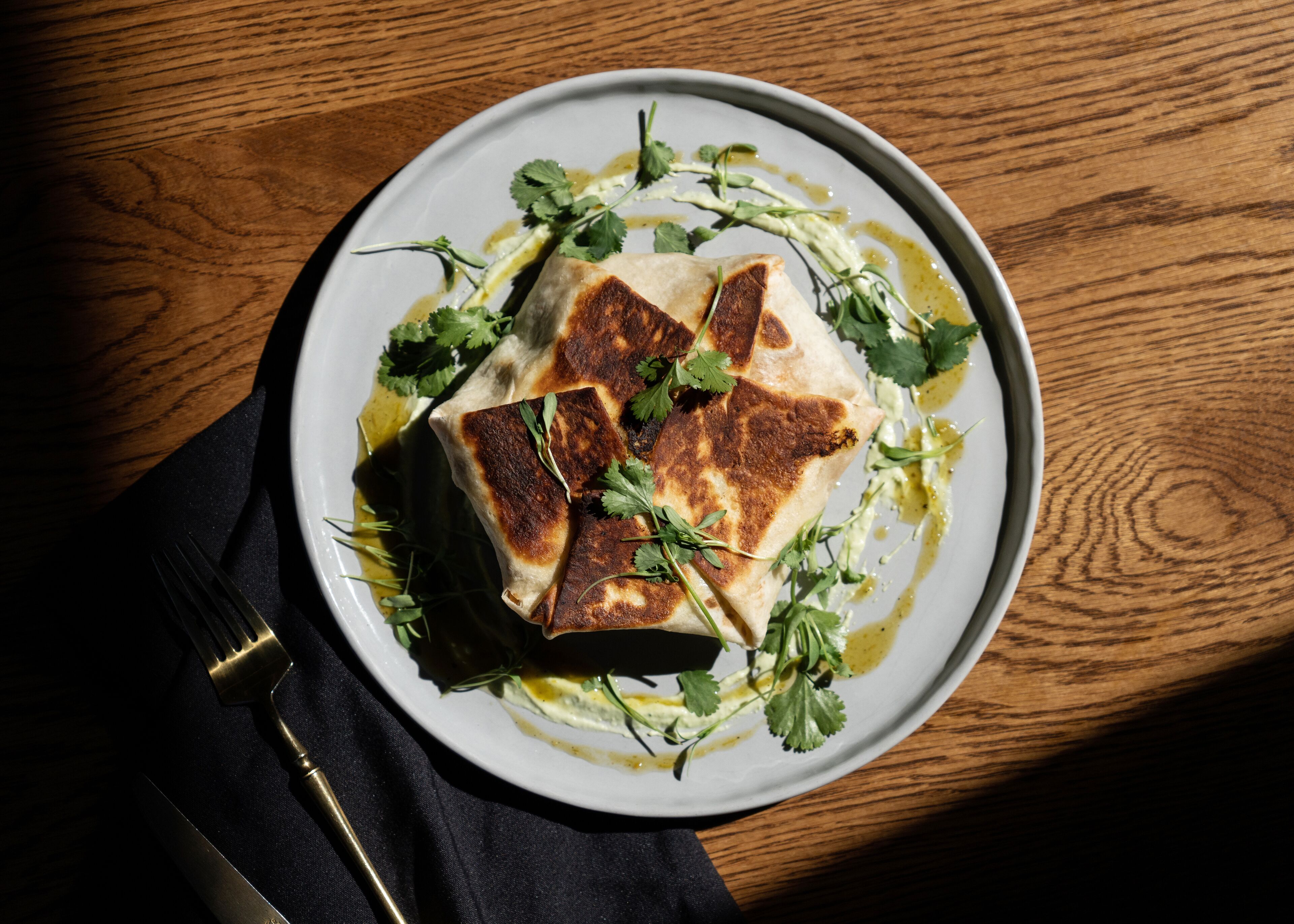 A plate of food with a fork and napkin on a wooden table.