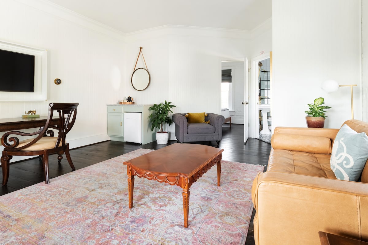 A living room with a wooden coffee table, a sofa, a chair, and a potted plant.