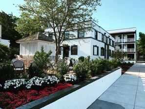 A modern two-story building with a white facade and black trim. There is a small garden with red and white flowers in front of the building. - ARRIVE Wilmington (Wilmington)