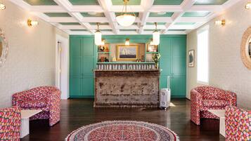 Quarto com paredes verde-água, um tapete estampado e duas cadeiras com padrão.