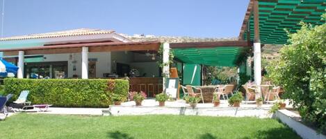 Un espace extérieur aménagé avec des sièges, un bar et une pergola couverte de verdure.