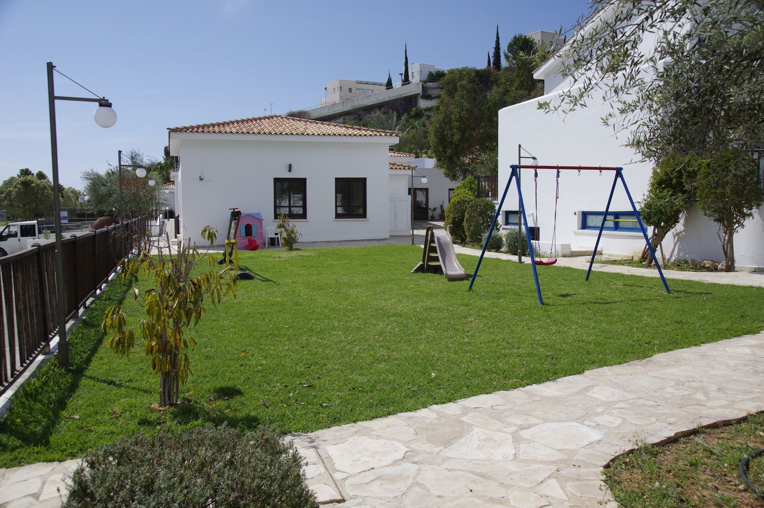 A residential area with a well-maintained lawn, a swing set, and a small playhouse.