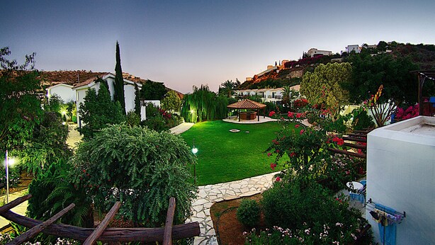A well-maintained garden with a stone pathway, a gazebo, and a variety of plants and flowers. - Hylatio Tourist Village (Pissouri)