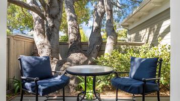 An outdoor patio with two blue chairs and a small round table.