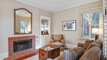 A living room with a fireplace, a sofa, a patterned armchair, and a coffee table.