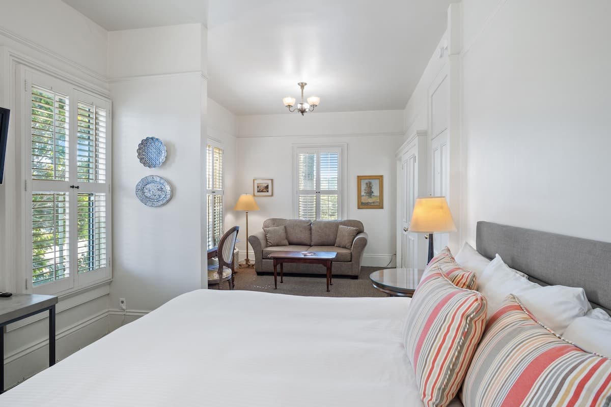 Une chambre d’hôtel avec un grand lit, un canapé, une petite table et deux lampes.