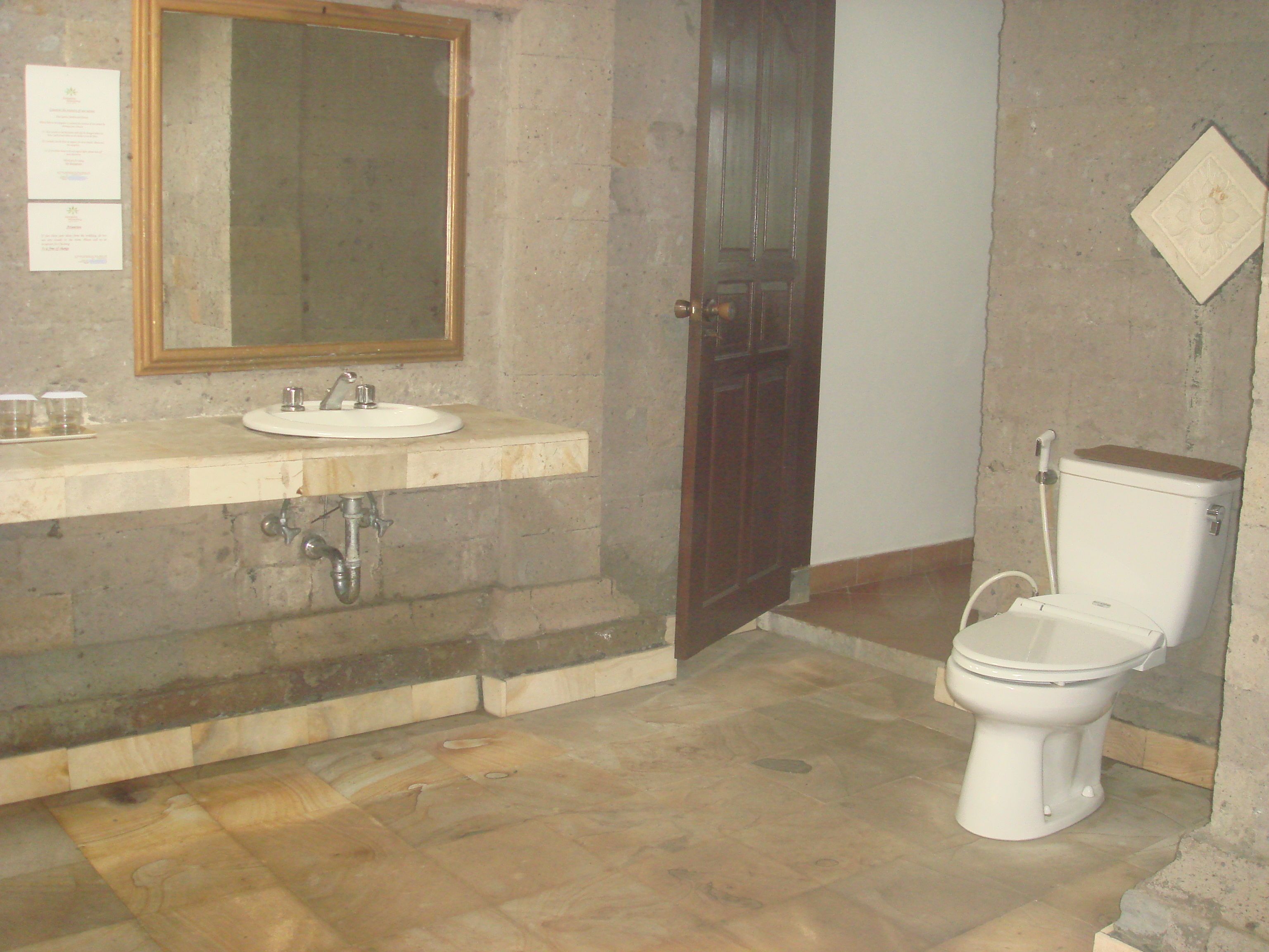 Un baño con lavamanos, espejo, inodoro y piso de madera.