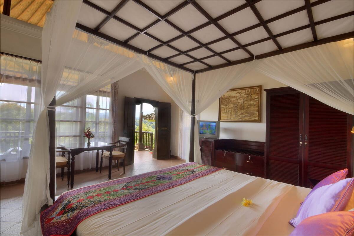 Een slaapkamer met een bed, bureau en televisie.