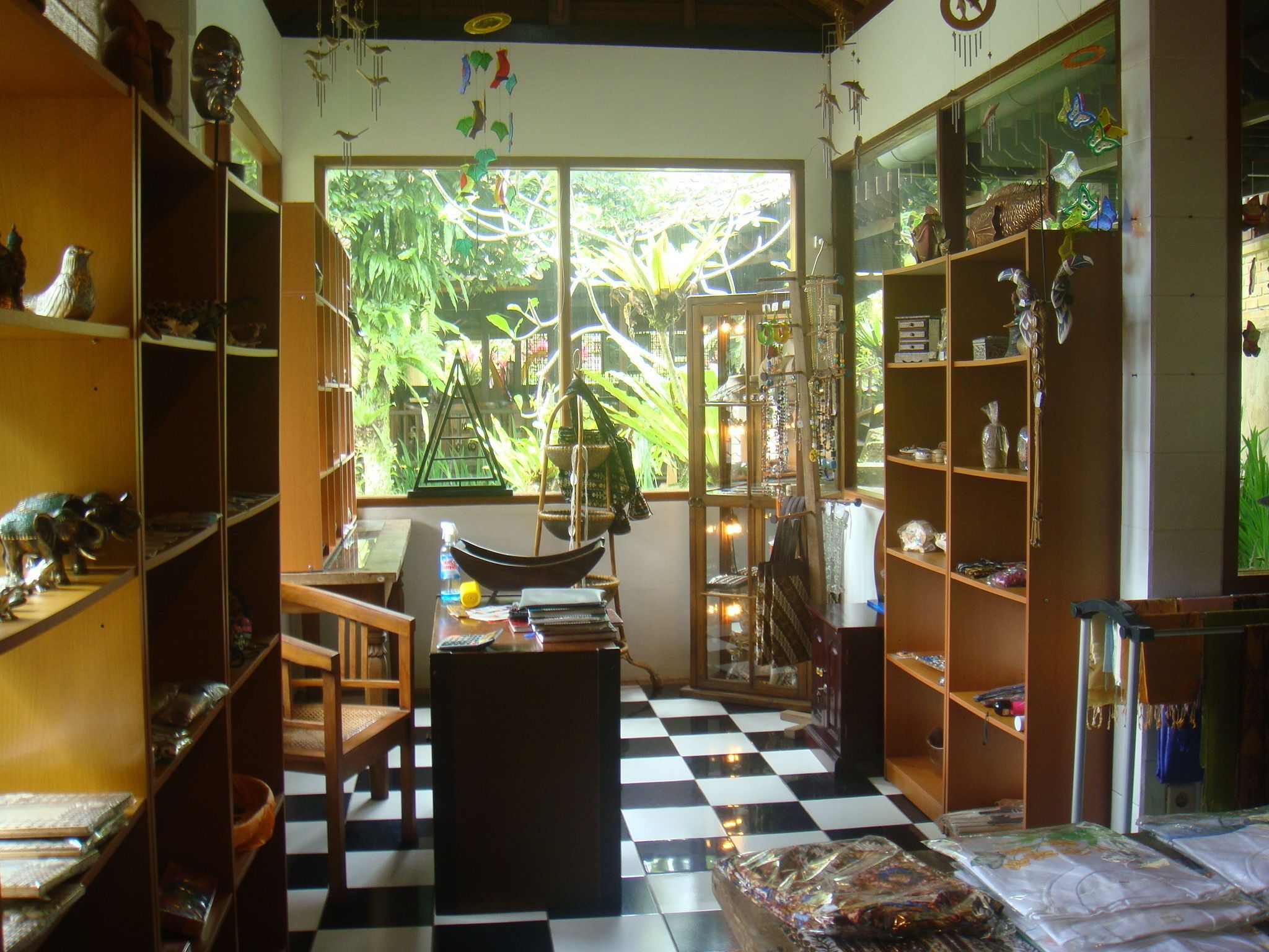 A room with a checkered floor, wooden furniture, and shelves filled with various items.