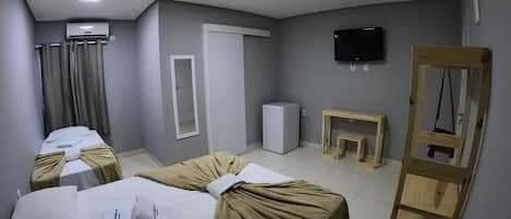 Una camera d'albergo con due letti, una televisione, uno specchio, un tavolino e una scala in legno.