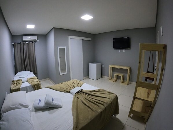A hotel room with two beds, a television, a mirror, a small table, and a wooden ladder.