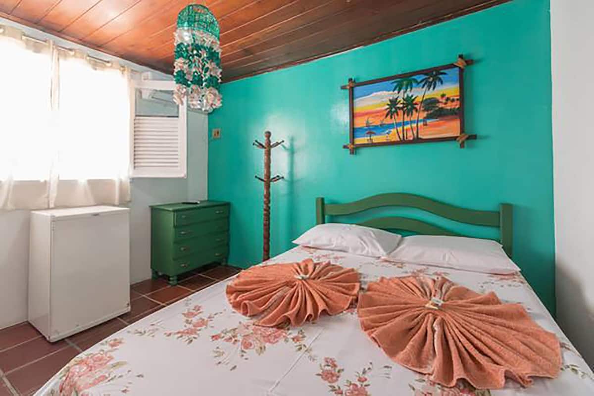 A bedroom with a bed, a dresser, a radiator, and a painting on the wall.