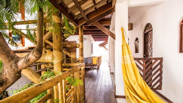 A wooden staircase with a hammock, surrounded by greenery and wooden railings. - Pousada João Sol (Mata de São João)