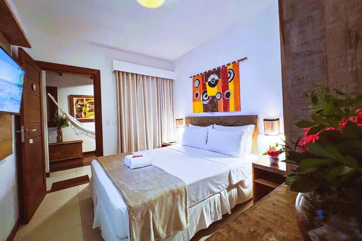 A hotel room with a bed, a TV, a painting, and a staircase.