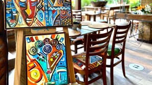 An art display with two paintings titled "Ateliê Dora Reuther" in a restaurant setting. - Pousada João Sol (Mata de São João)