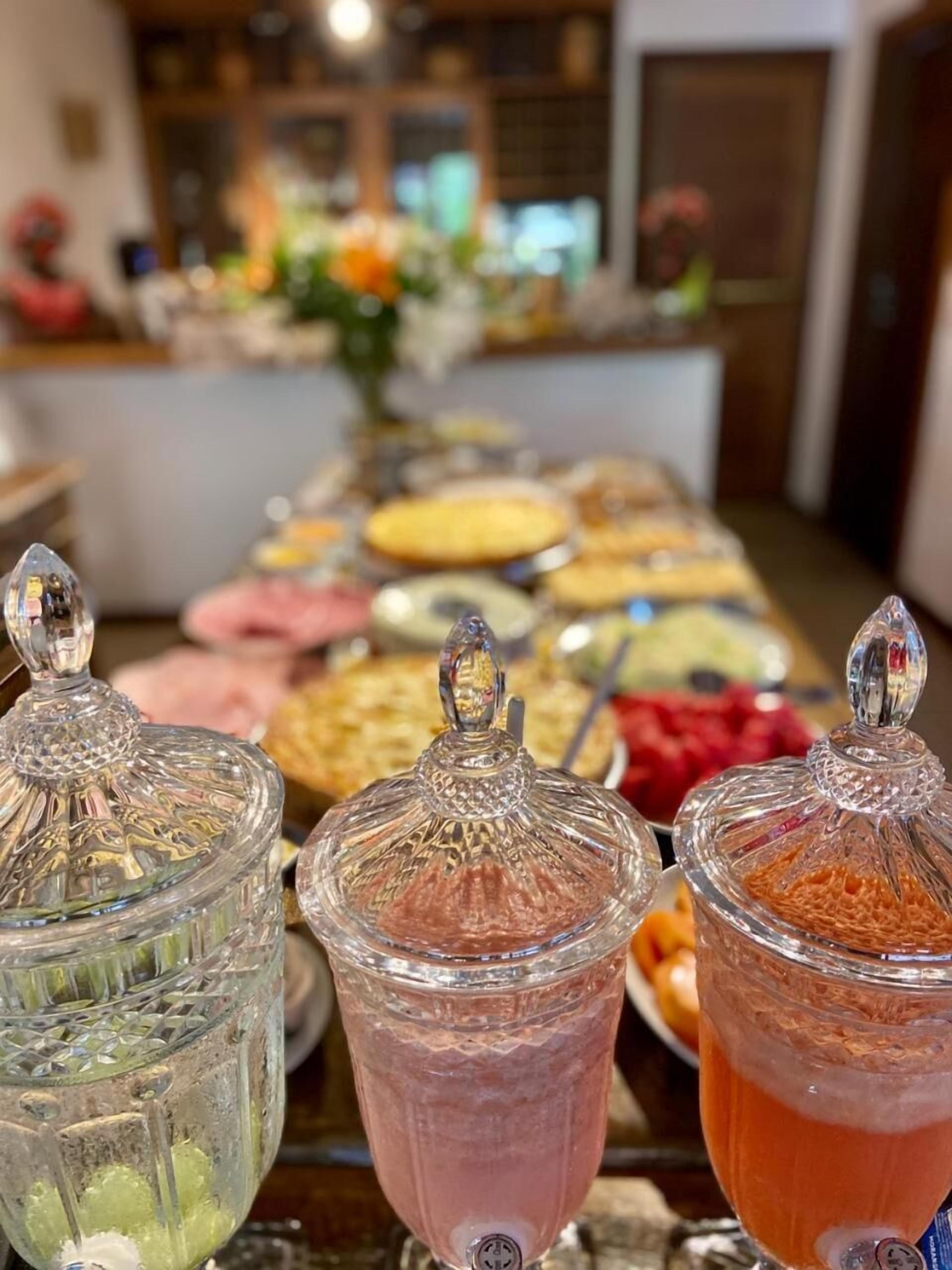 A buffet table with various food items and three glass containers with lids.