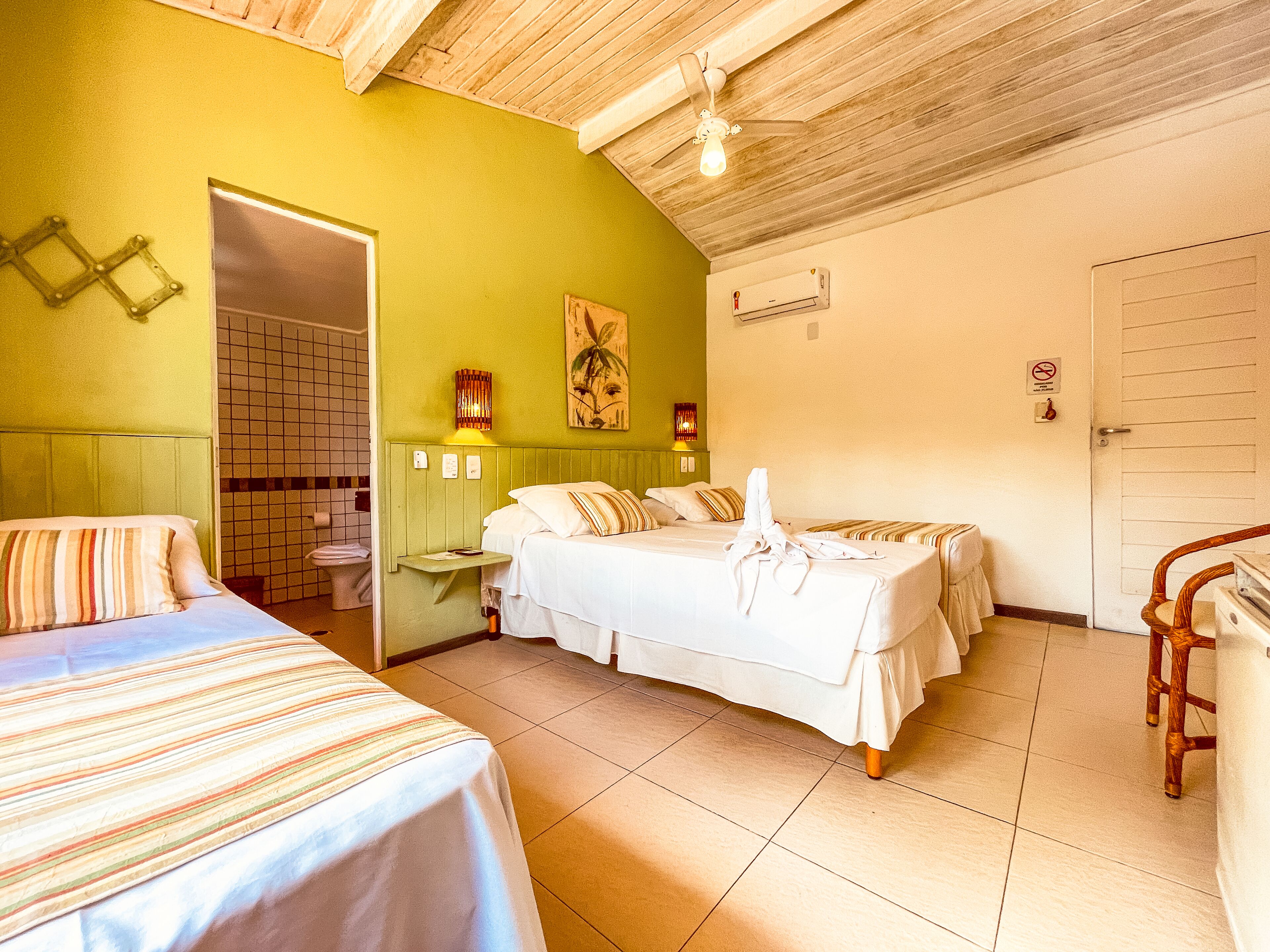 A hotel room with two beds, a wooden ceiling, and a tiled floor.