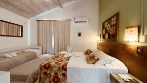 Een hotelkamer met twee bedden, een houten hoofdbord, een klein tafeltje en een wandairconditioner.