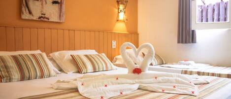 A hotel room with a bed featuring striped bedding, a wall-mounted air conditioner, and a painting above the bed.