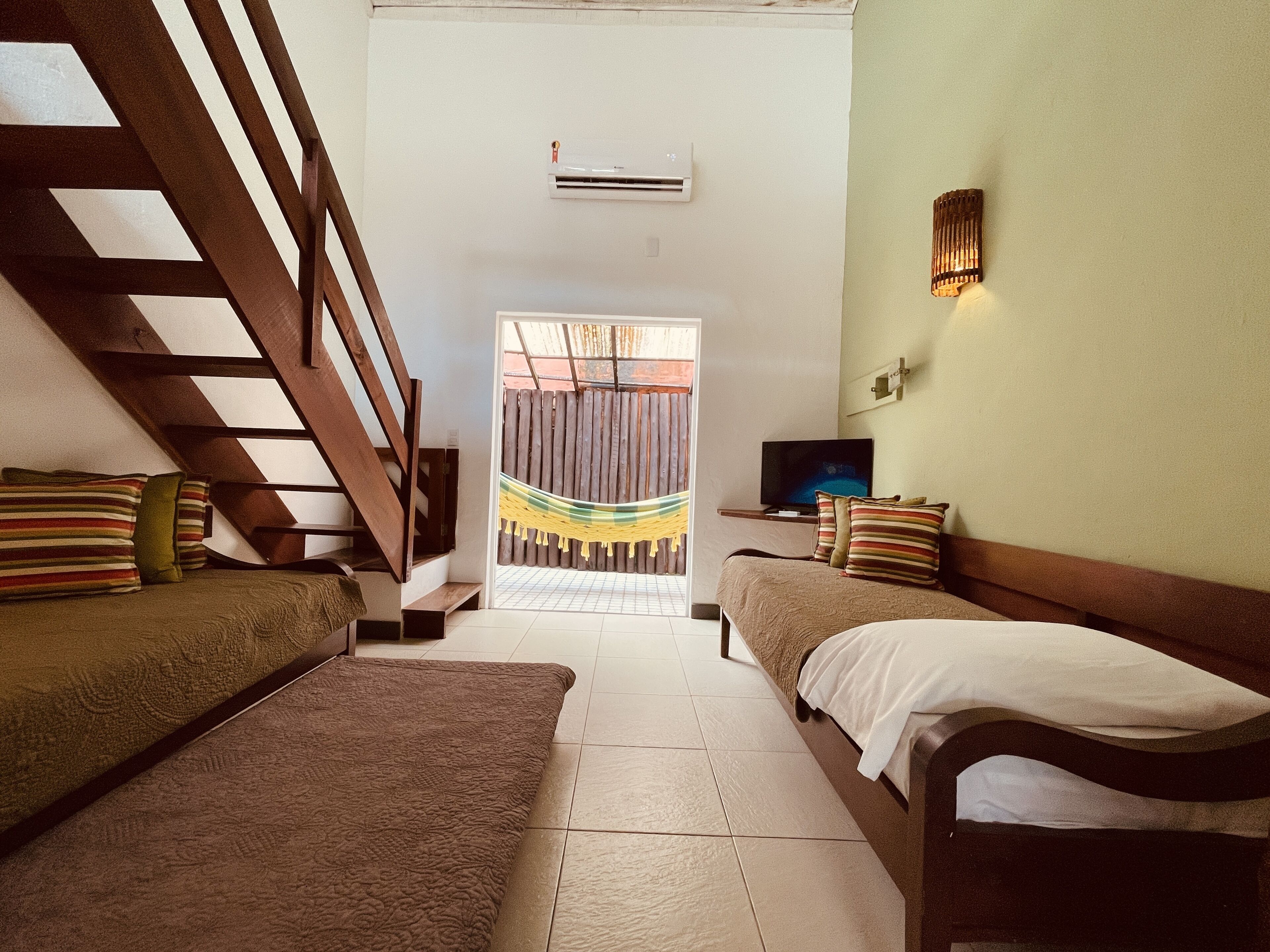 A room with two beds, a TV, and a staircase.