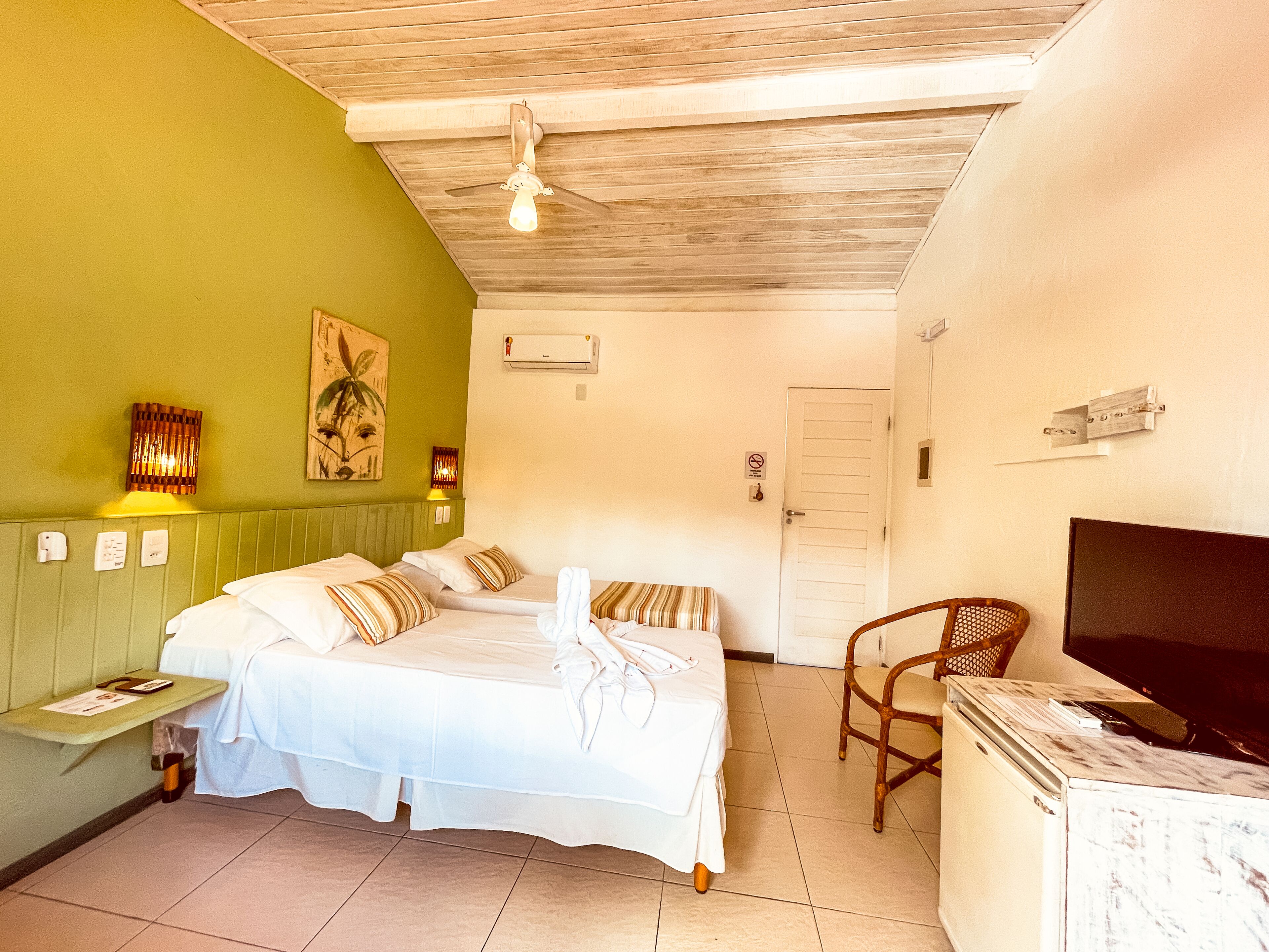 A hotel room with two beds, a TV, a chair, and a small table.