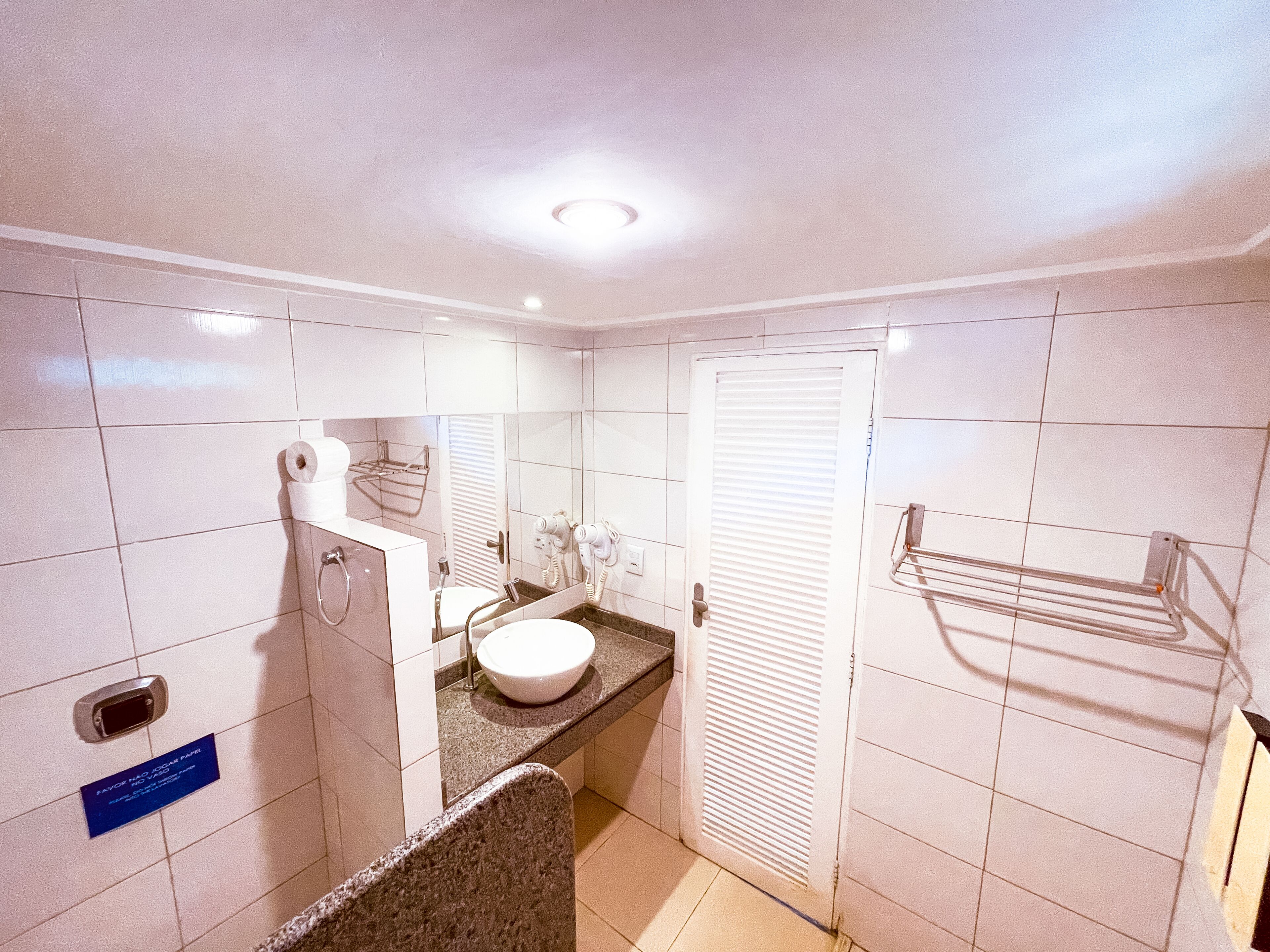 Un bagno compatto con lavandino, specchio, porta asciugamani e una porta con portasciugamani.