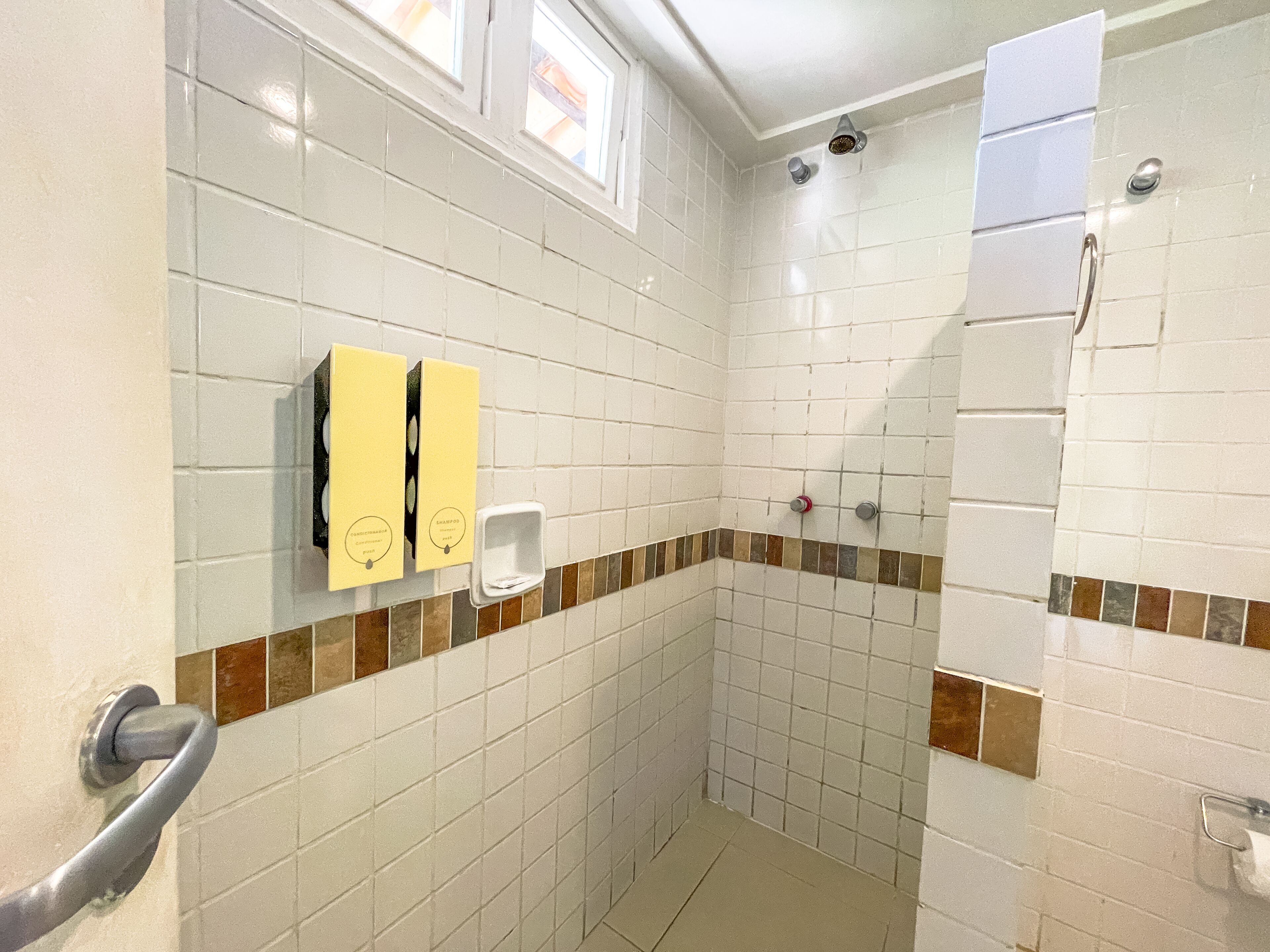 Un baño con azulejos blancos, zona de ducha y un perchero para toallas.