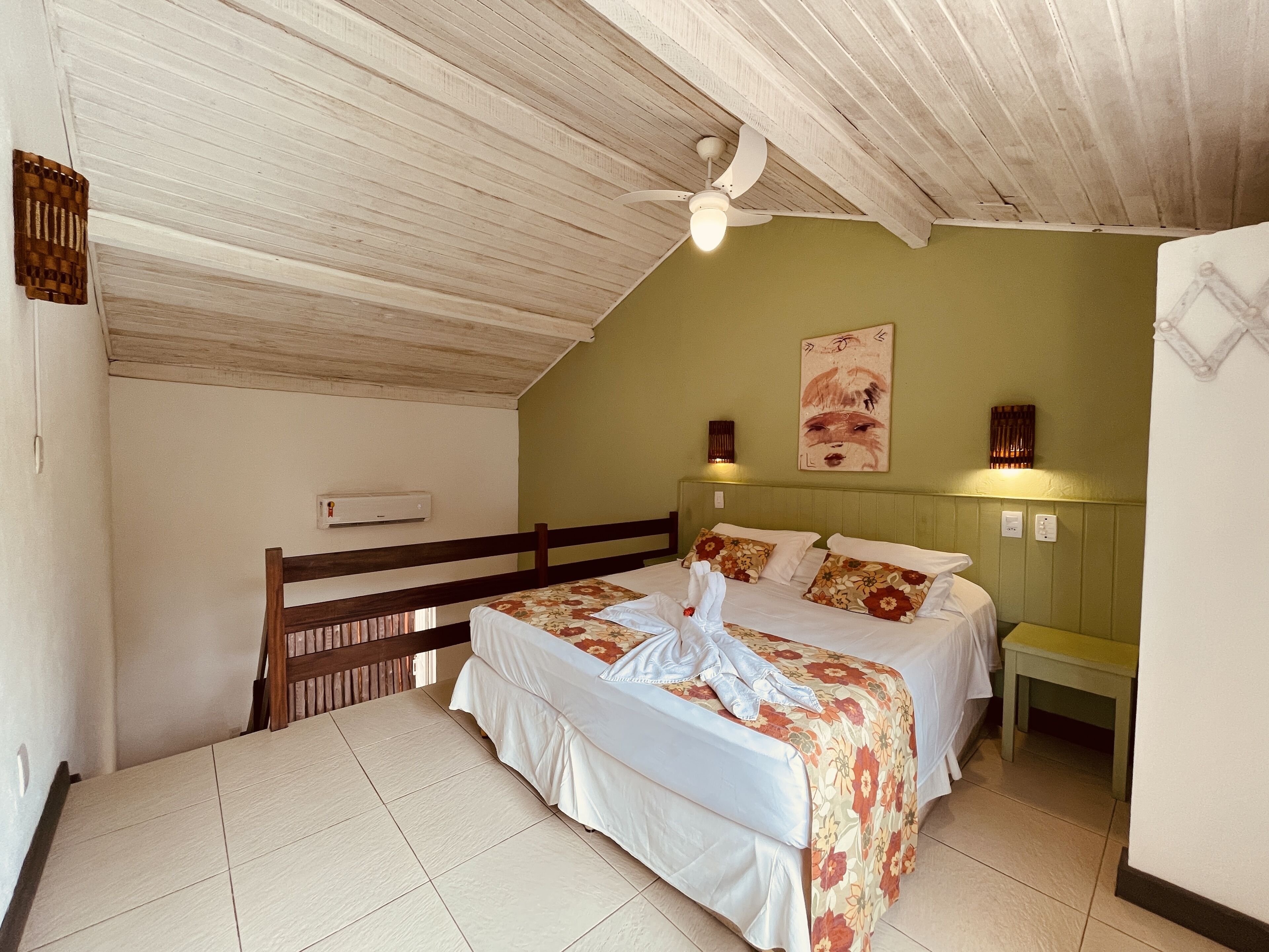 Una habitación con dos camas, ventilador de techo, aire acondicionado de pared y un cuadro.