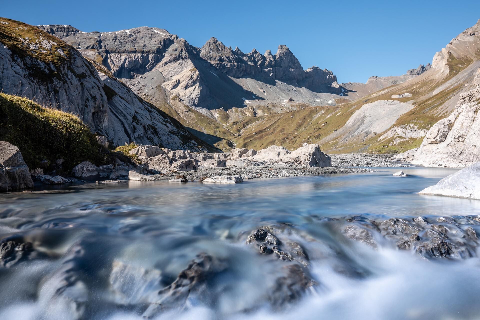 Un río serpentea por un paisaje montañoso con terreno rocoso y cielos despejados.
