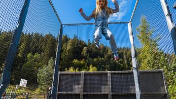Jump into fun with a trampoline enclosure featuring a safety net and padded surface.