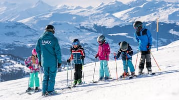 Eine Gruppe von Skifahrern auf einem verschneiten Hang, mit Bergen im Hintergrund.