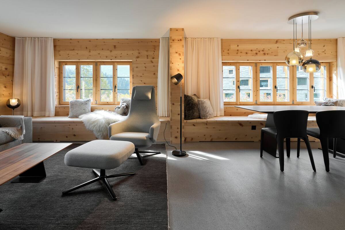 A modern interior with a wooden wall, a sofa, a dining table with chairs, and a floor lamp.