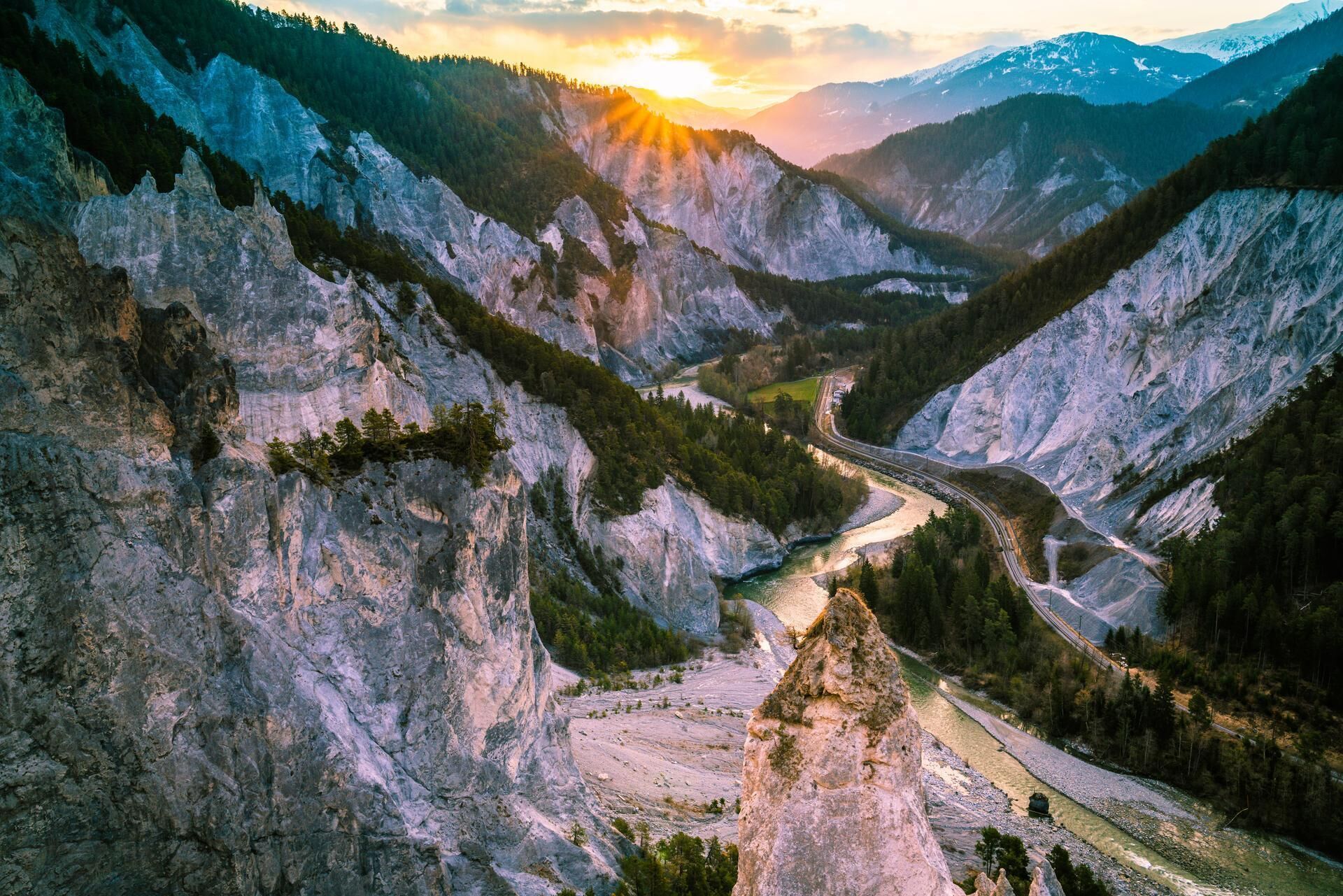 Eine gebirgige Landschaft mit einer kurvenreichen Straße und einem Fluss.