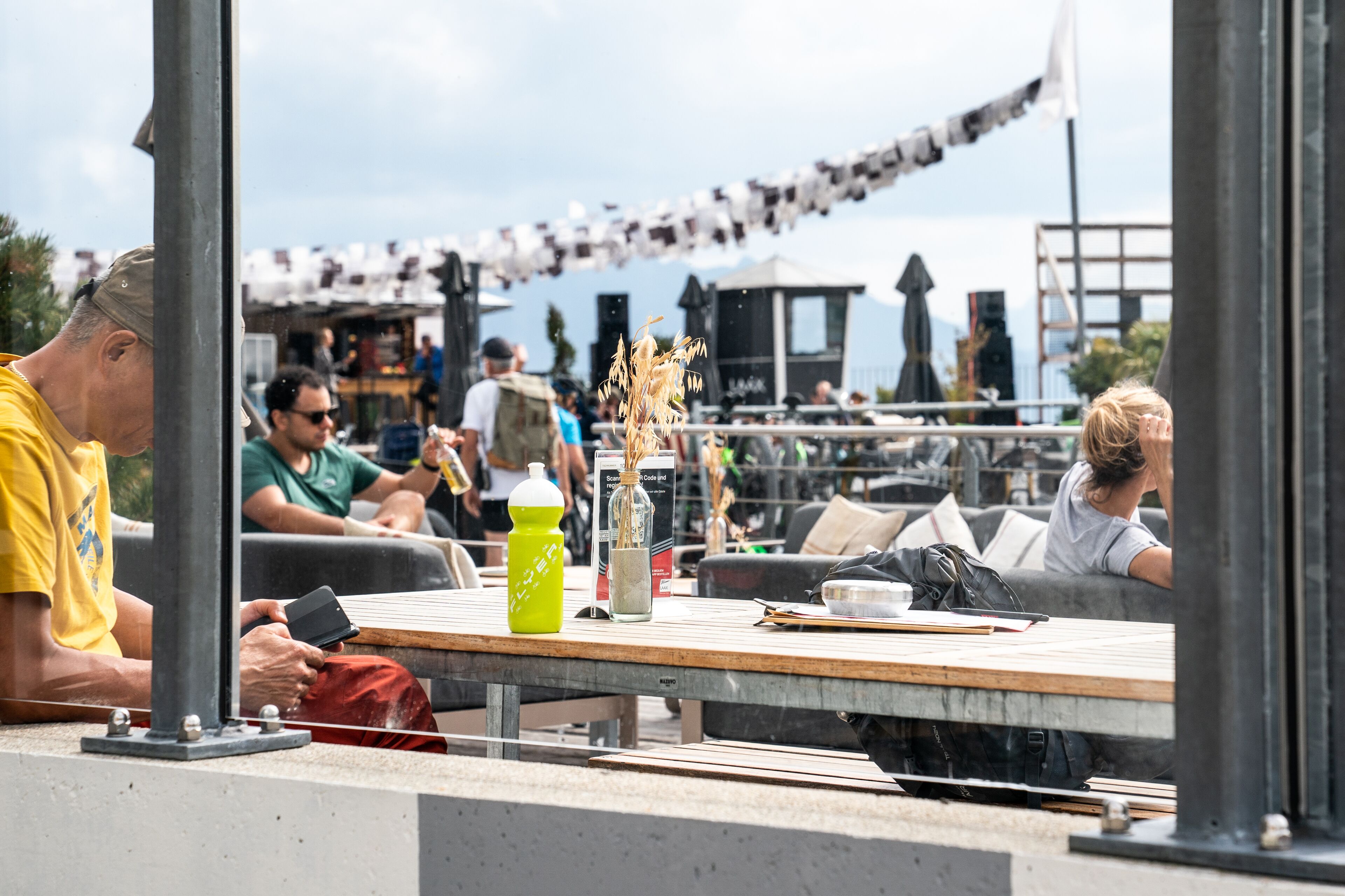 An outdoor seating area with tables and chairs, a green bottle, and a vase with dried plants.