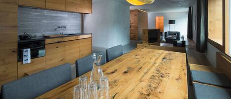 A modern kitchen with wooden cabinets, a large wooden dining table, and a hanging pendant light.