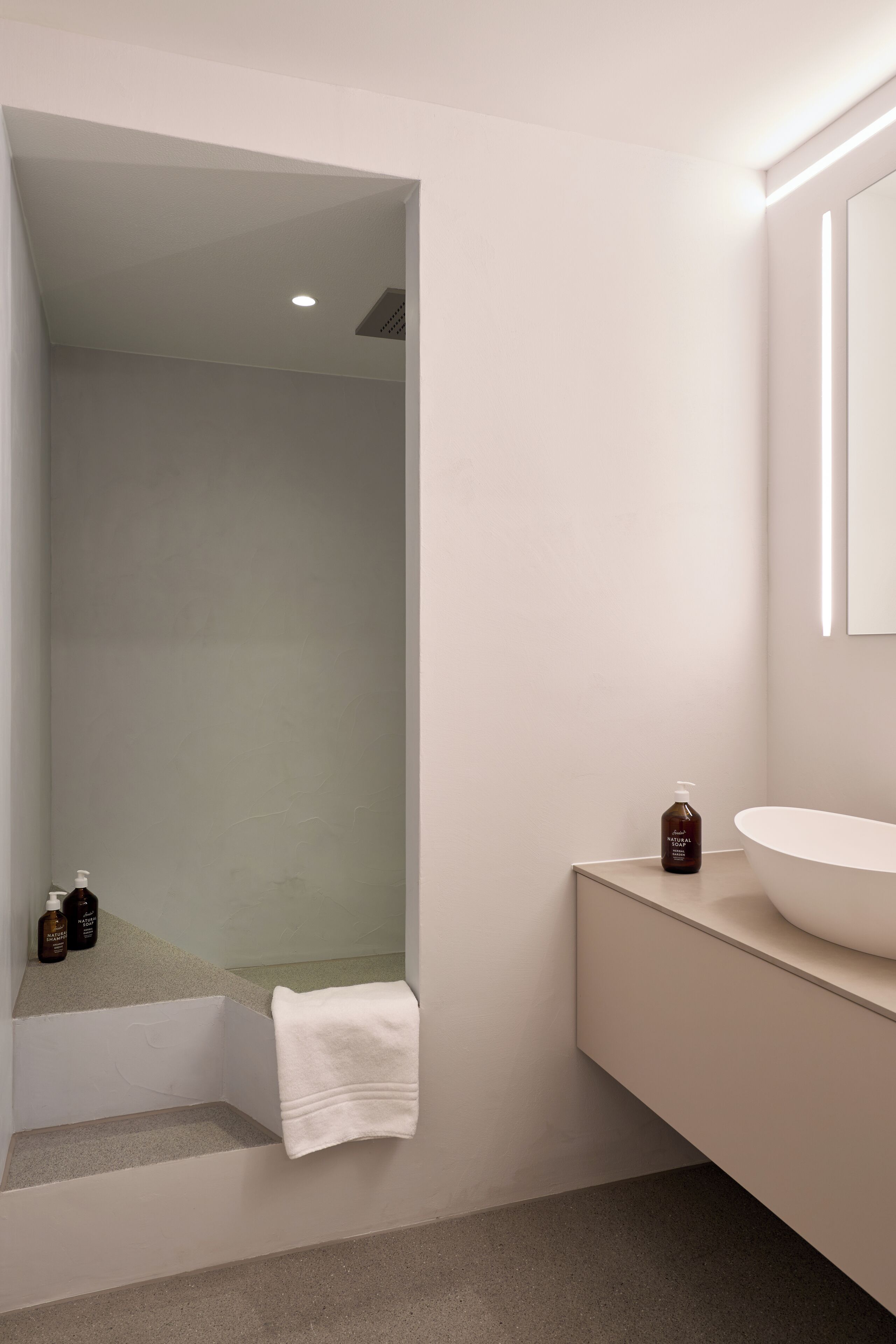 A modern bathroom with a glass-enclosed shower, a white sink, and a mirror above it.