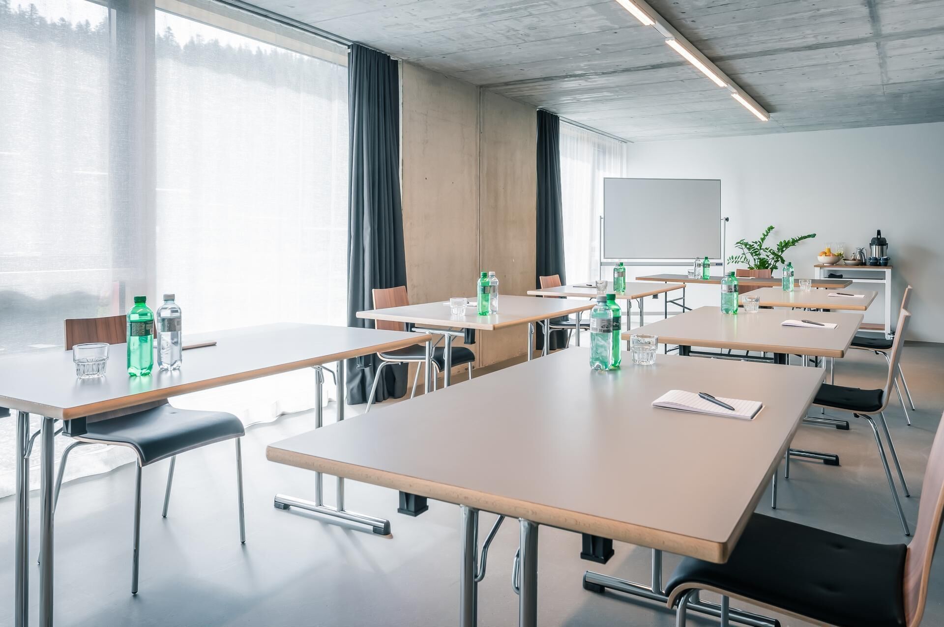 A conference room with long tables, chairs, and a whiteboard.