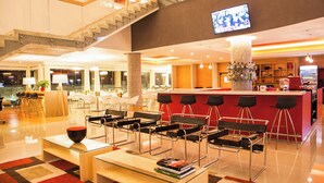 A modern hotel lobby with a staircase, seating area, bar, and a large TV screen. - Fiesta Inn Queretaro Centro Sur (Querétaro)