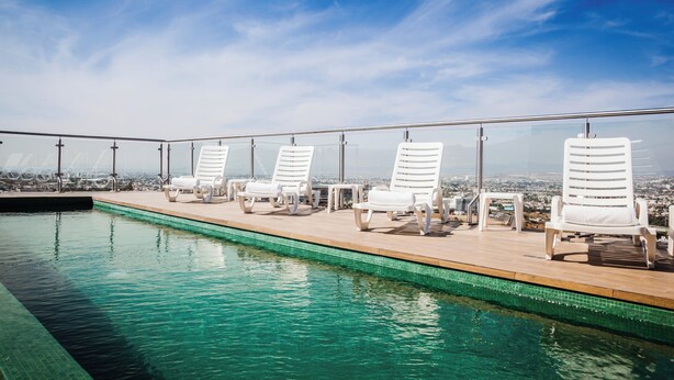 A rooftop pool with white lounge chairs and a city view. - Fiesta Inn Queretaro Centro Sur (Querétaro)