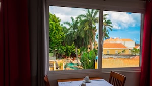 Un comedor con mesa y sillas, una ventana que ofrece vistas a un jardín y edificios.