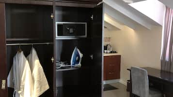 Quarto de hotel com closet espaçoso, micro-ondas, tábua de passar, escrivaninha e uma cadeira.