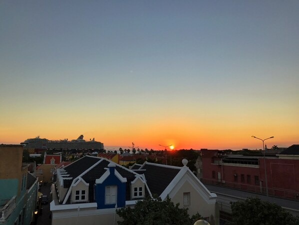 A coastal town at sunset with colorful buildings and a cruise ship docked. - Curacao Suites Hotel (Willemstad)