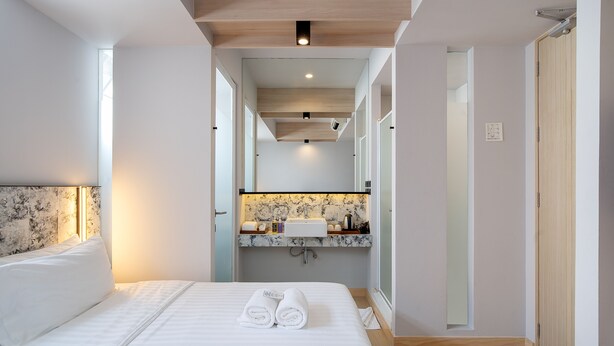 Une chambre d’hôtel moderne, dotée d’un lit, d’une salle de bain avec un lavabo et un miroir, et d’un plafond en bois.