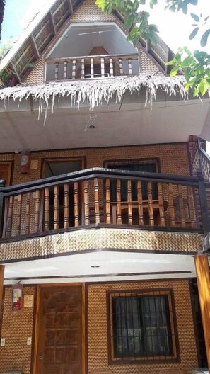 A two-story building with a balcony featuring wooden balusters and a white railing.