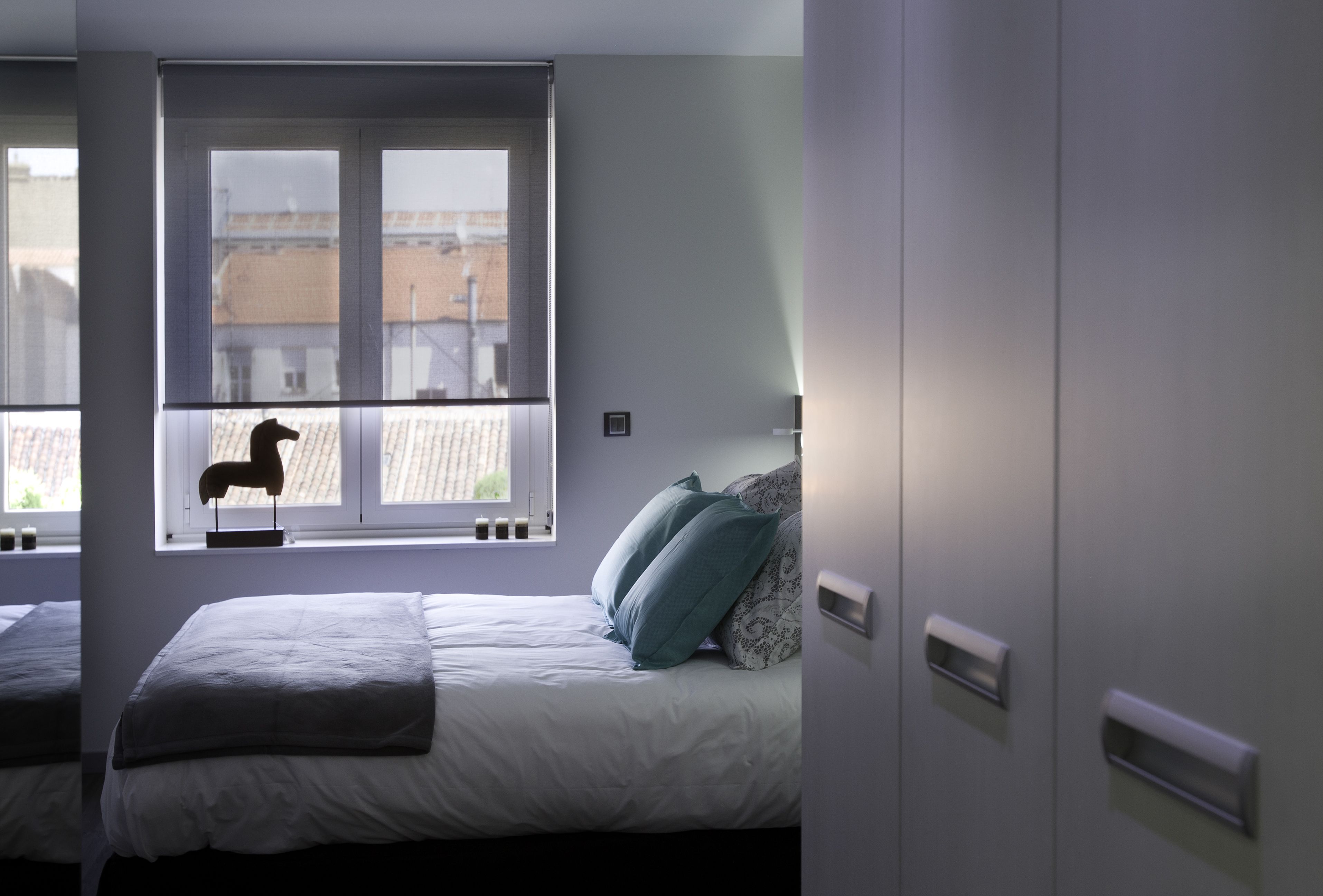 Ein Schlafzimmer mit Bett, Fenster und Blick auf Gebäude.