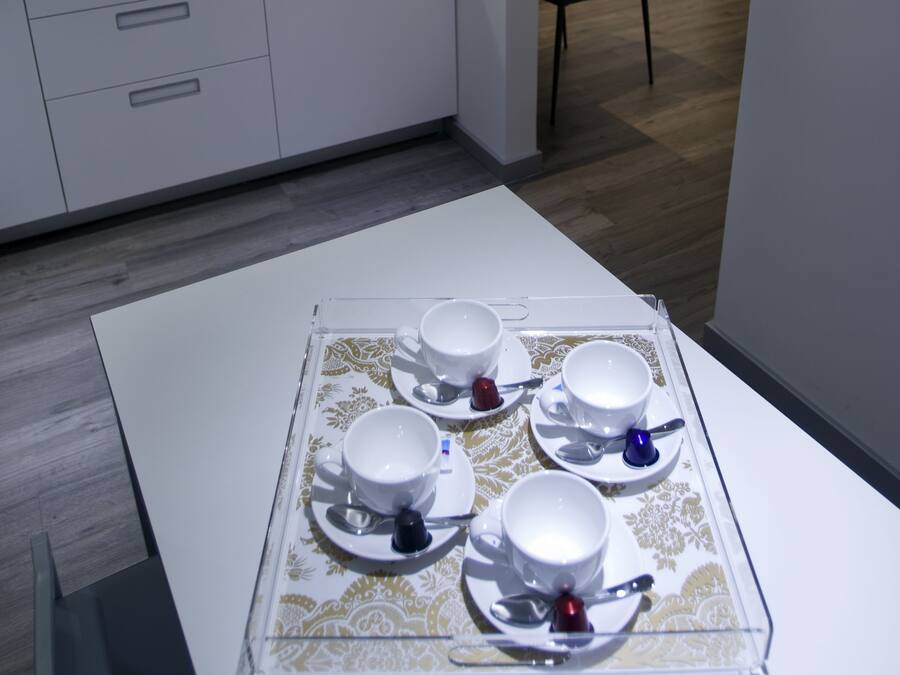 Una habitación de hotel moderna con una cama blanca, una mesita de noche y un pequeño rincón de estar.